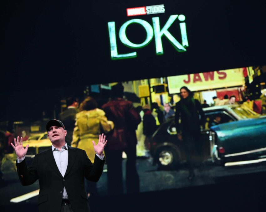 Photo de Kevin Feige devant un logo et un concept art pour la série Loki