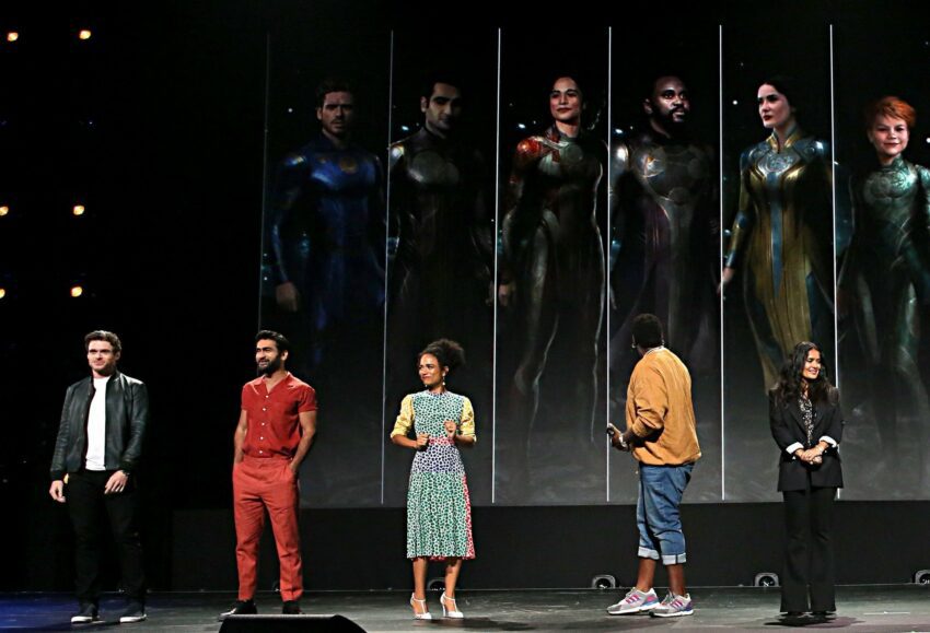 Photo du panel Marvel Studios au D23 pour le film The Eternals avec les acteurs devant un concept art des costumes